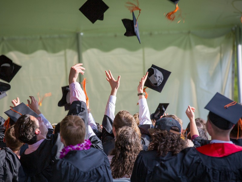 MBA graduates tossing graduation hats