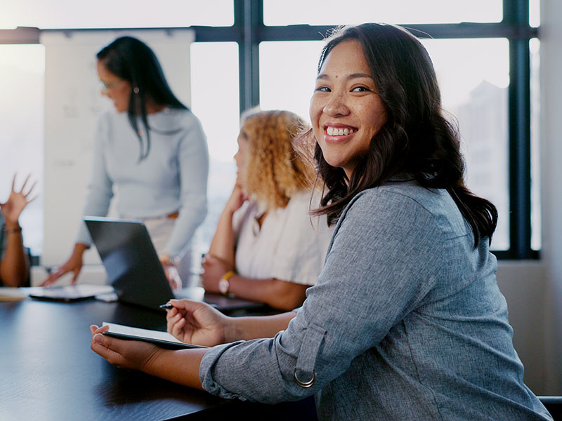 Professional woman taking notes during a business meeting, representing personalized career coaching and strategic planning in an online MBA program.