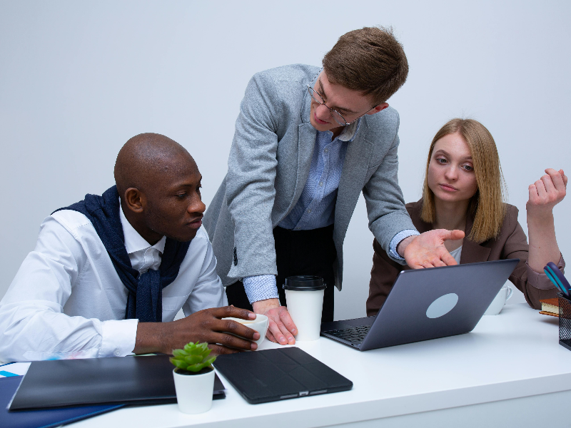 Three professionals discussing career strategies in a modern office setting, emphasizing online MBA education as a catalyst for career change and advancement.