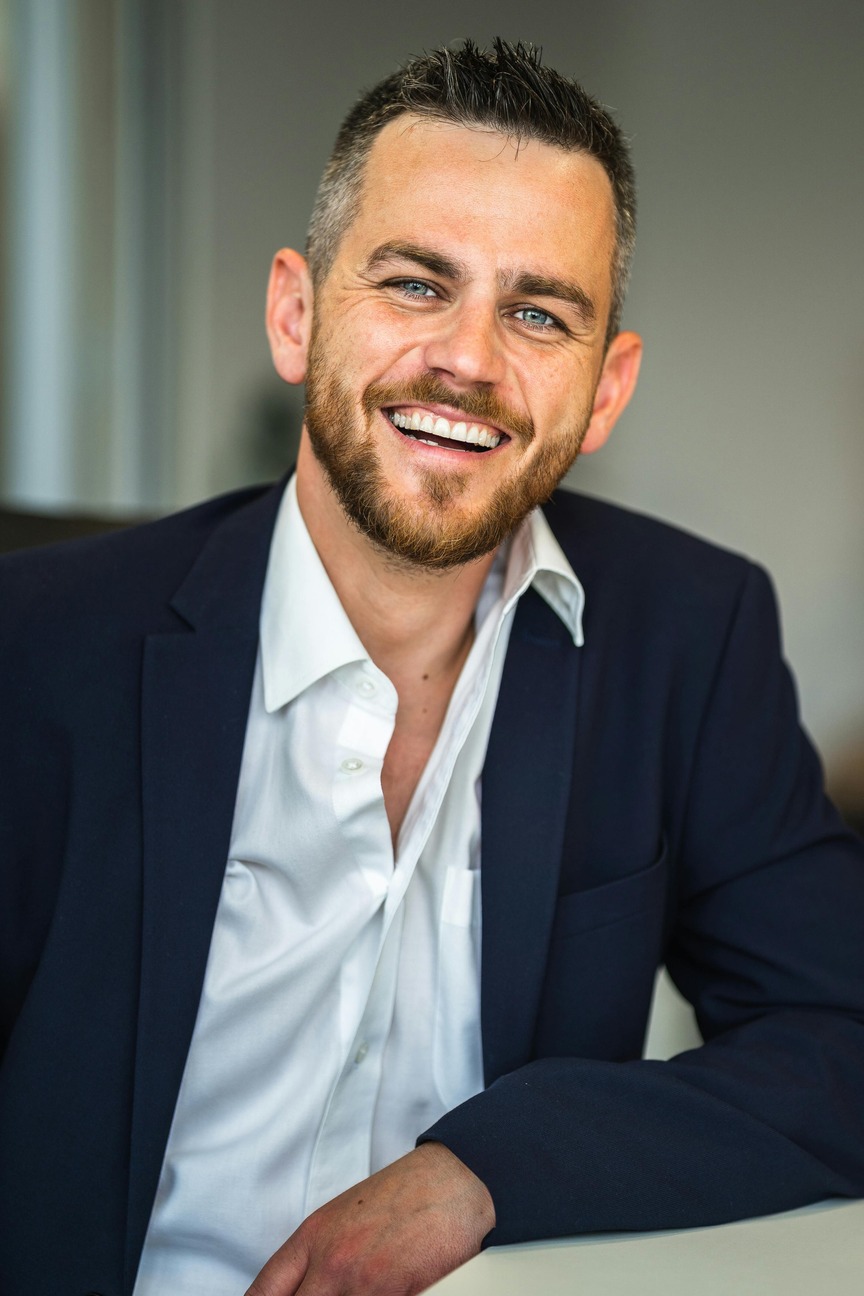 A professional in a dark blue suit and white shirt sits at a desk in an office setting, symbolizing career opportunities and professionalism associated with an MBA in Finance.